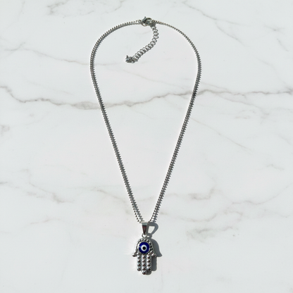 Silver diamond-cut hamsa evil eye necklace on white marble individual showcase