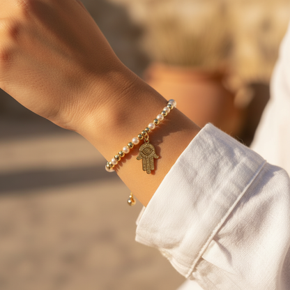 Pearl and gold hamsa bracelet worn on wrist in golden hour Mediterranean light