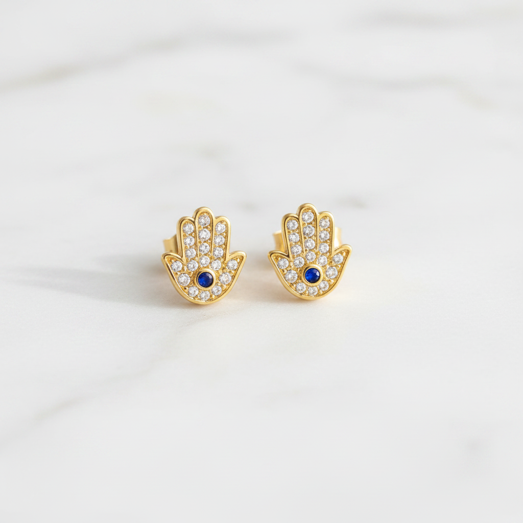Hamsa gold stud earrings on clean white marble