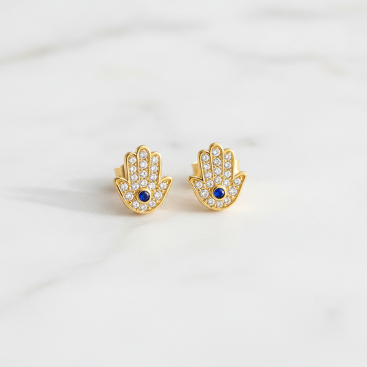 Hamsa gold stud earrings on clean white marble