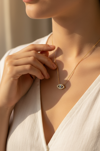 Woman touching gold evil eye necklace at collarbone