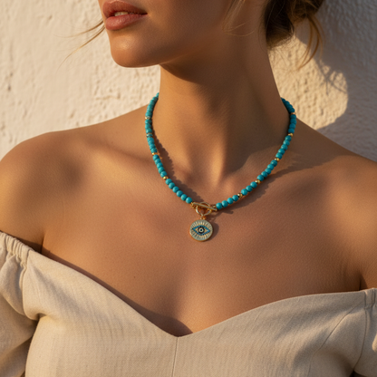 Turquoise evil eye necklace worn on collarbone against sunlit whitewashed Mediterranean wall