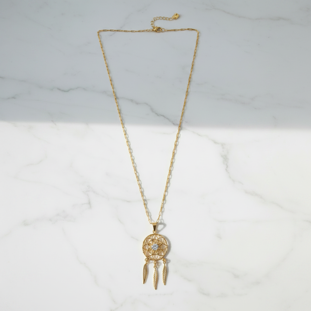 Gold dreamcatcher necklace on white marble surface, clean overhead shot