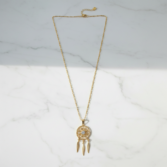 Gold dreamcatcher necklace on white marble surface, clean overhead shot