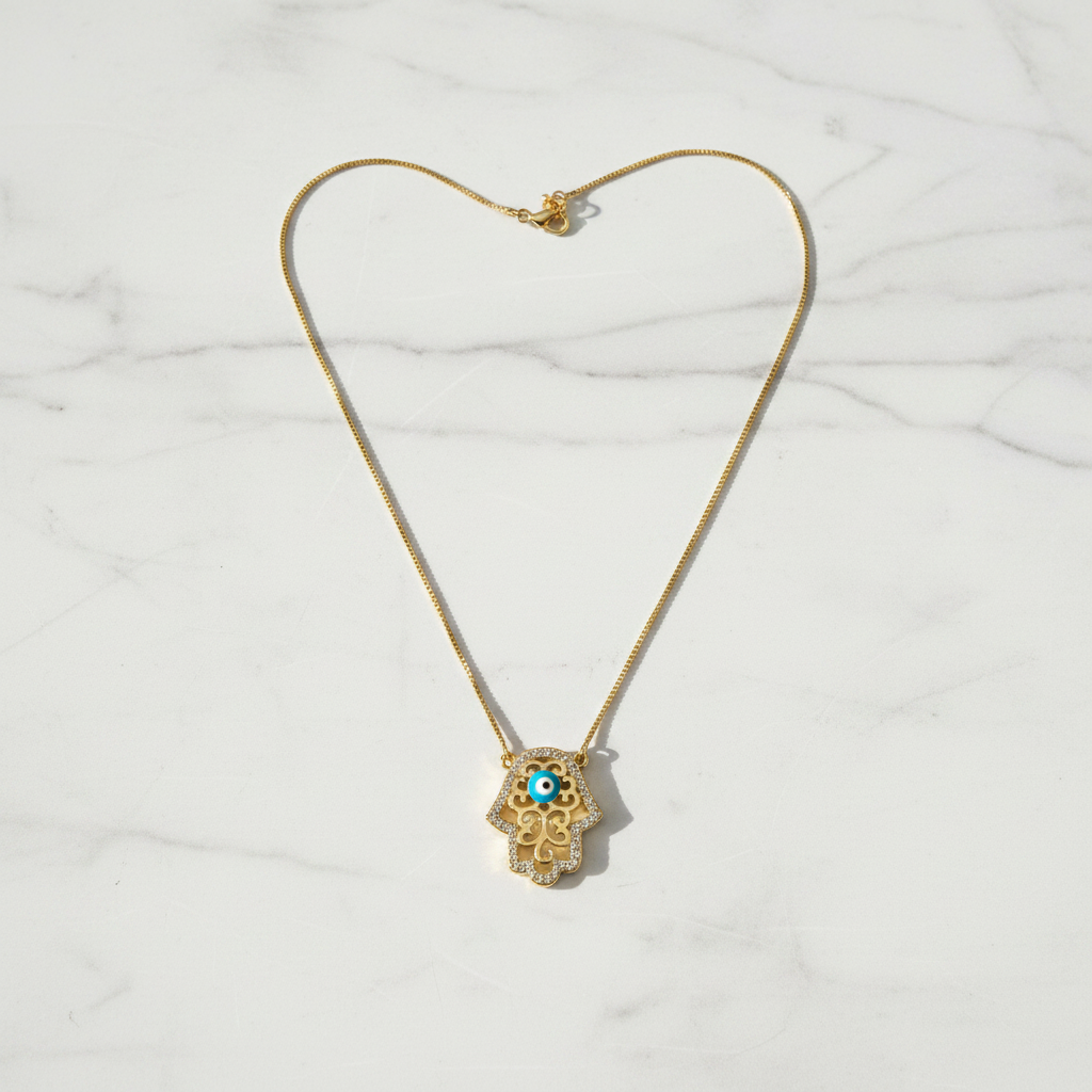 Hamsa evil eye necklace on white marble surface, clean overhead shot