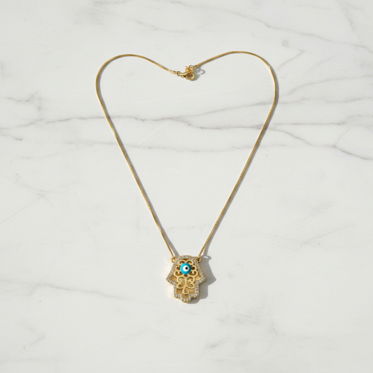 Hamsa evil eye necklace on white marble surface, clean overhead shot