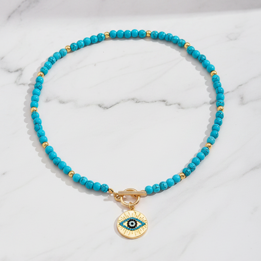 Turquoise evil eye necklace flat lay on white marble background