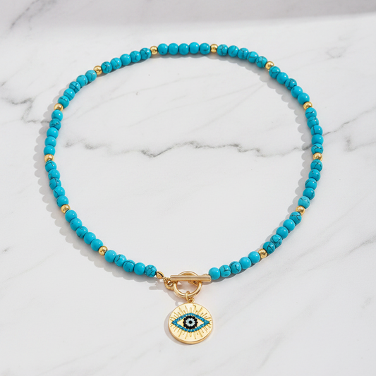 Turquoise evil eye necklace flat lay on white marble background