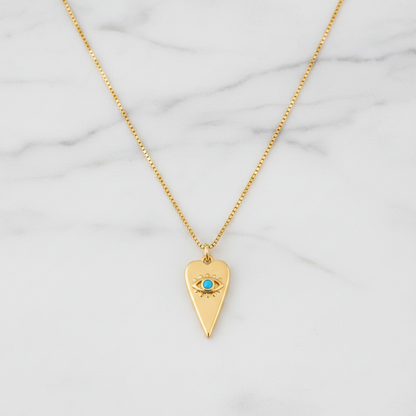 Gold heart evil eye necklace with turquoise stone flat lay on white marble