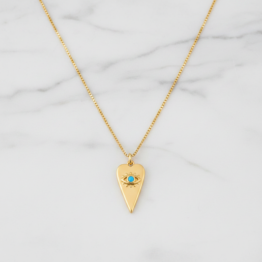 Gold heart evil eye necklace with turquoise stone flat lay on white marble