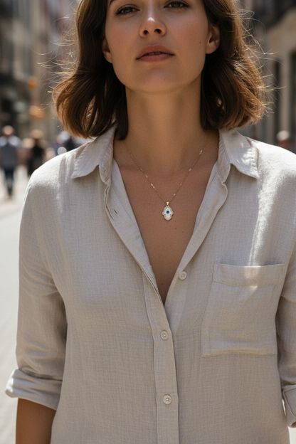 Woman walking on sunny street wearing white enamel Hamsa evil eye necklace