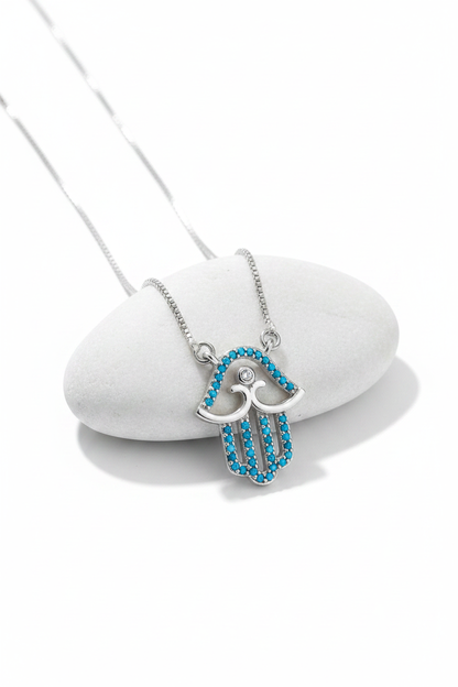 Silver turquoise hamsa necklace on white display stand, clean showcase shot