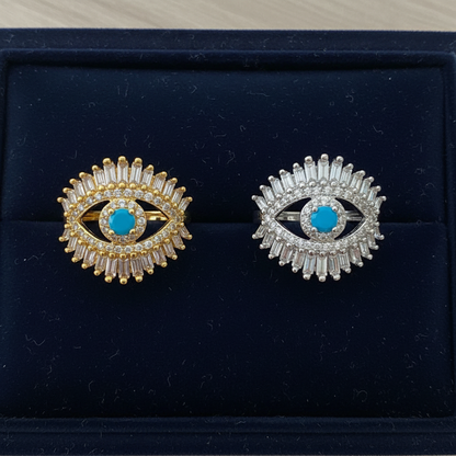 Gold and silver baguette evil eye cocktail rings side by side on navy velvet luxury display