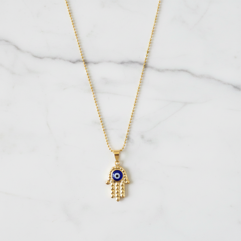 Gold diamond-cut hamsa evil eye necklace on white marble individual showcase
