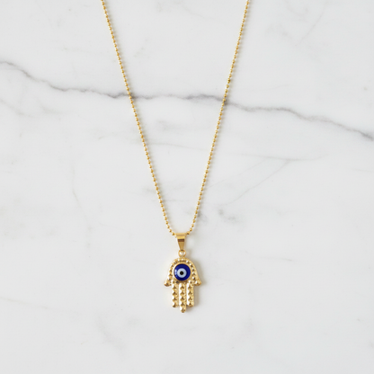Gold diamond-cut hamsa evil eye necklace on white marble individual showcase