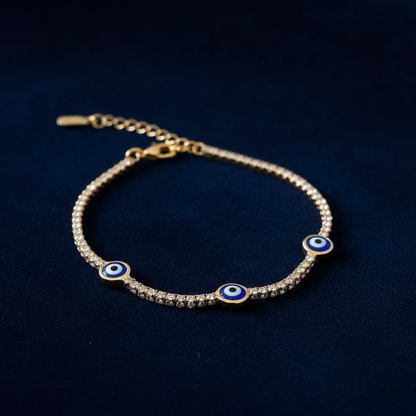 Gold evil eye tennis bracelet on dark navy velvet luxury showcase