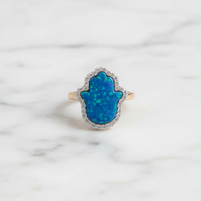 Blue opal hamsa ring flat lay on marble