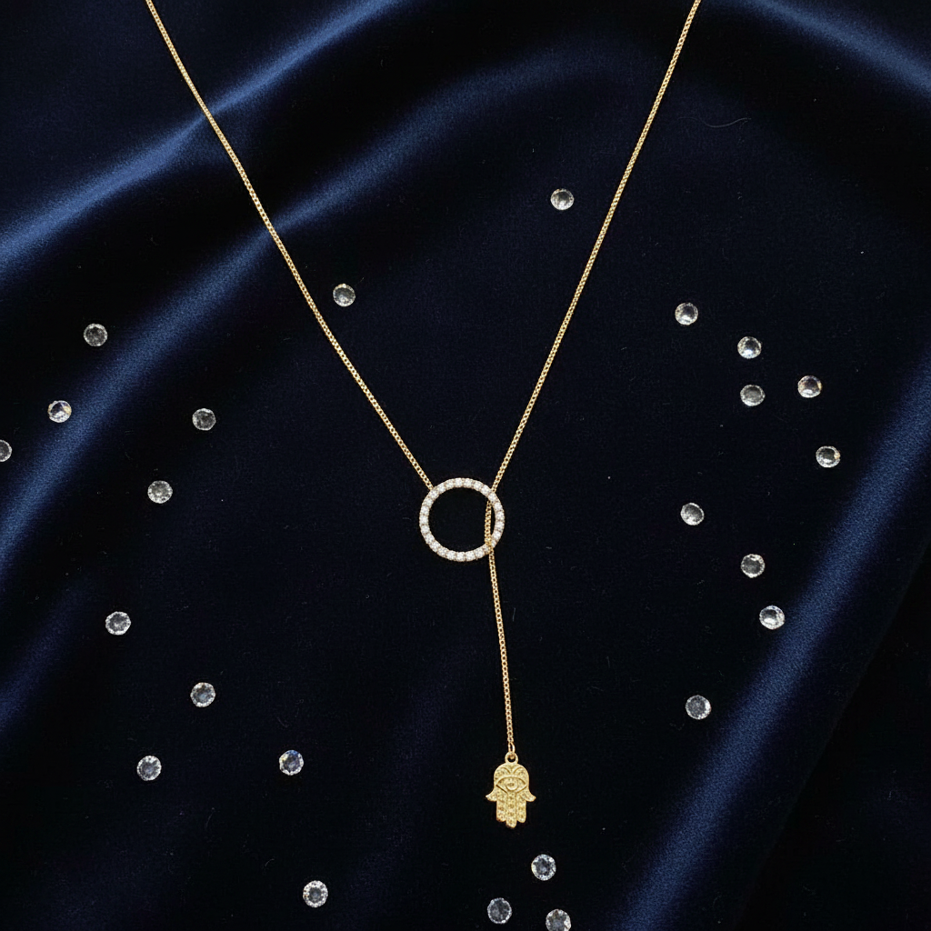 Gold hamsa lariat necklace flat lay on navy velvet with crystals