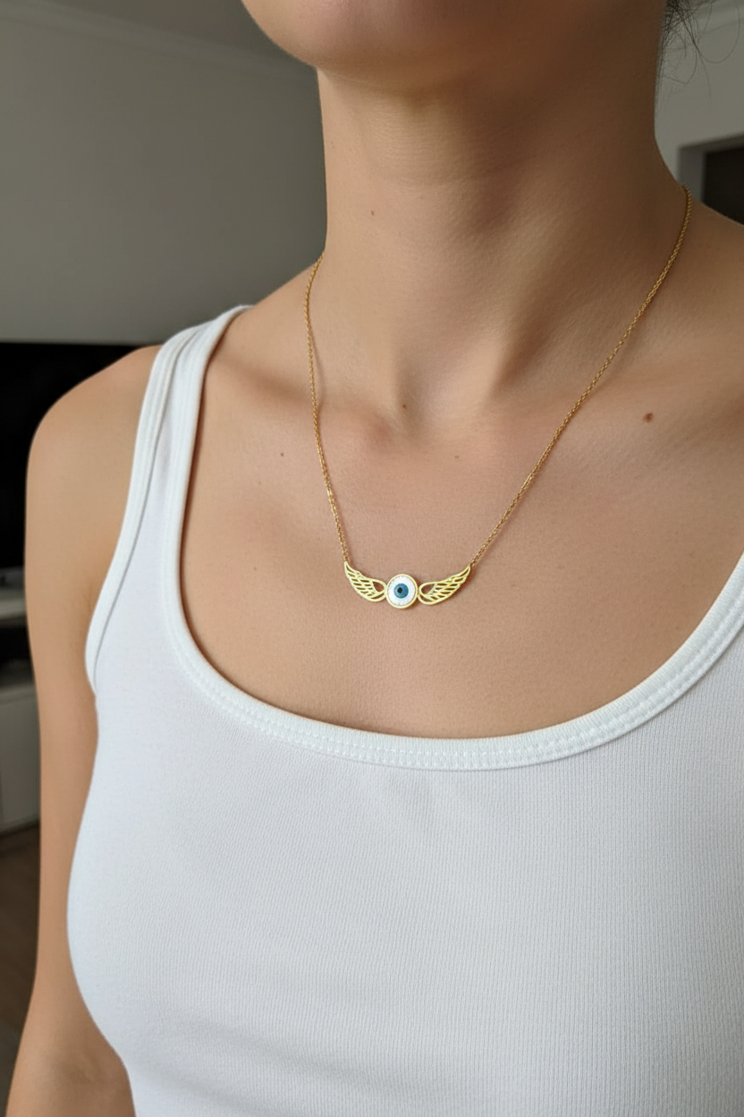 Woman wearing evil eye angel wings necklace, white tank top