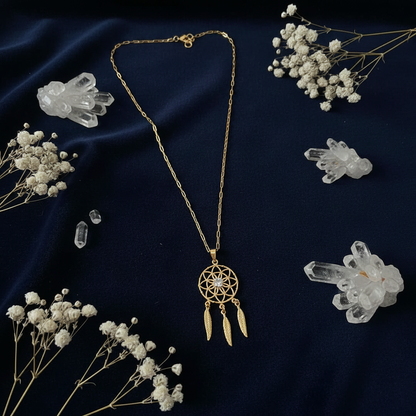 Flat lay of gold dreamcatcher necklace on dark navy velvet with crystals