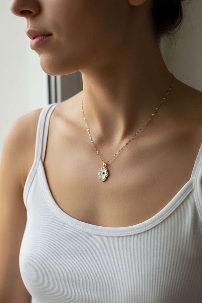 Woman wearing white enamel Hamsa evil eye necklace, white tank top